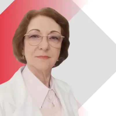 Doctora Alicia Gorzelewski con bata blanca, lentes y expresión profesional frente a fondo geométrico en tonos rojo y gris.